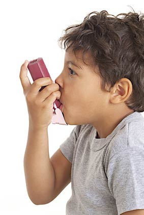 Young boy using his asthma inhaler to treat an asthma attack